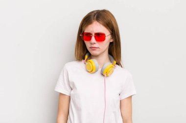 Kızıl saçlı güzel kız üzgün, üzgün ya da kızgın ve yana bakıyor. müzik konseptini dinle
