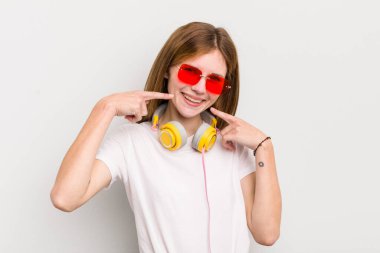 Kızıl saçlı güzel kız, kendine güvenerek gülümseyerek kendi gülüşünü gösteriyor. müzik konseptini dinle