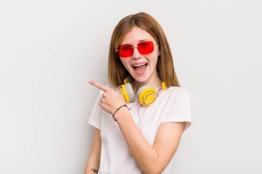 Kızıl saçlı güzel kız heyecanlı ve şaşırmış görünüyor. müzik konseptini dinle