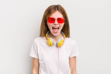 Kızıl saçlı güzel kız agresif bir şekilde bağırıyor, çok kızgın görünüyor. müzik konseptini dinle