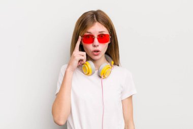 Kızıl saçlı güzel kız şaşırmış görünüyor, yeni bir düşünceyi, fikri ya da konsepti fark ediyor. müzik konseptini dinle