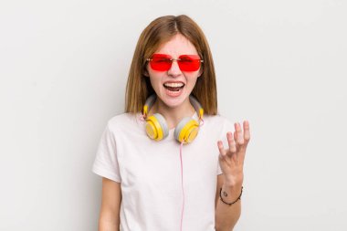 Kızıl saçlı güzel kız sinirli, sinirli ve sinirli görünüyor. müzik konseptini dinle