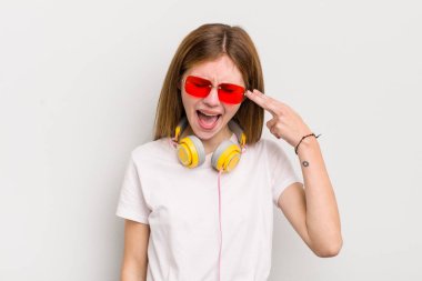 Kızıl saçlı güzel kız mutsuz ve stresli görünüyor, intihar jesti silah işareti yapıyor. müzik konseptini dinle