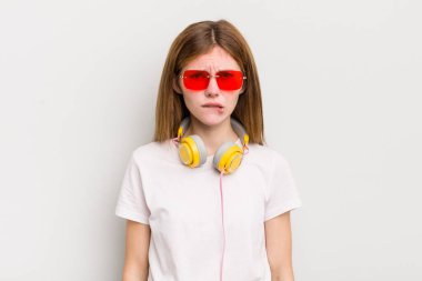 Kızıl saçlı güzel kız şaşkın ve şaşkın görünüyor. müzik konseptini dinle