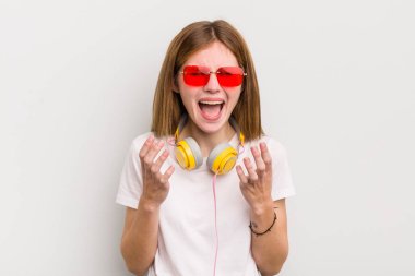 Kızıl saçlı güzel kız umutsuz, hayal kırıklığına uğramış ve stresli görünüyor. müzik konseptini dinle