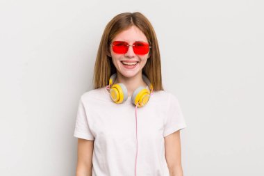 Kızıl saçlı güzel kız mutlu ve hoş bir şekilde şaşırmış görünüyor. müzik konseptini dinle