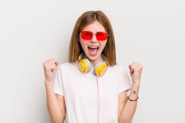 Kızıl saçlı güzel kız sinirli bir ifadeyle agresif bir şekilde bağırıyor. müzik konseptini dinle