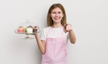 Kızıl saçlı güzel kız seni seçen kamerayı işaret ediyor. Ev yapımı kek konsepti