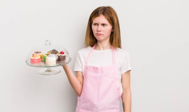 Kızıl saçlı güzel kız üzgün, üzgün ya da kızgın ve yana bakıyor. Ev yapımı kek konsepti