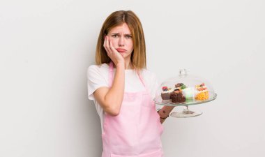 Kızıl saçlı güzel bir kız bıkkın, yorgun ve uykulu hissediyor. Ev yapımı kek konsepti