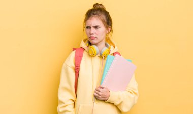 Kızıl saçlı güzel kız üzgün, üzgün ya da kızgın ve yana bakıyor. öğrenci konsepti