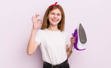 Kızıl saçlı güzel kız kendini mutlu hissediyor, iyi bir jestle onaylıyor. kahya konsepti