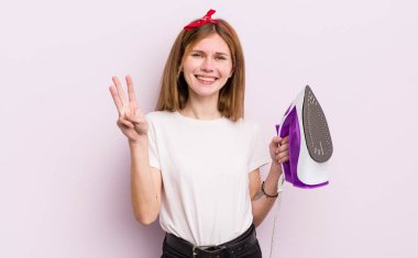 kızıl saçlı güzel kız gülümsüyor ve arkadaş canlısı görünüyor, üç numarayı gösteriyor. kahya konsepti