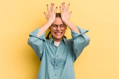 Genç ve güzel bir kadın stresli ve endişeli, depresif ve hayal kırıklığına uğramış hissediyor, iki elini de başa kaldırıyor.