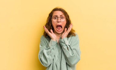 Genç ve güzel bir kadın beklenmedik bir sürpriz yüzünden şaşkın, heyecanlı, gülen, şaşkın ve mutlu hissediyor.