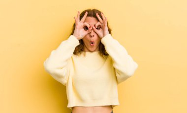 Genç, güzel bir kadın şaşkın, şaşırmış ve şaşırmış hissediyor. Elinde şaşkın, inançsız bir bakışla gözlük tutuyor.