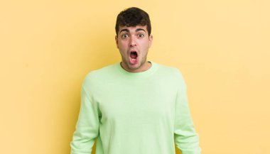 Genç ve yakışıklı bir adam şok olmuş ya da şaşırmış görünüyor, ağzı açık bir şekilde 
