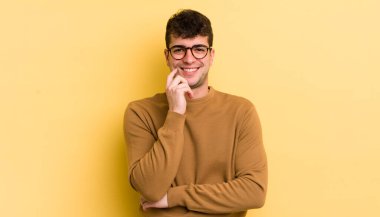 Genç yakışıklı adam gülümsüyor, hayattan zevk alıyor, mutlu, arkadaş canlısı, tatmin olmuş ve tasasız.