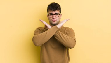 Genç ve yakışıklı adam senin tavırlarından rahatsız ve bıkkın görünüyor, yeter artık! Eller önde çapraz, durmanı söylüyor.