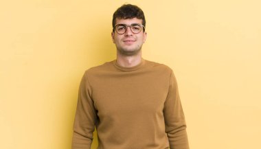 Genç yakışıklı adam pozitif ve kendinden emin gülümsüyor. Tatmin olmuş, arkadaş canlısı ve mutlu görünüyor.