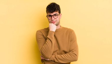 Genç yakışıklı adam ciddi görünüyor, kafası karışık, kararsız ve düşünceli, seçenekler ve seçimler arasında şüpheci.