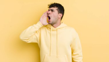 Genç yakışıklı adam öfkeyle bağırıyor kenardaki boşluğu kopyalasın diye, eli ağzının yanında.