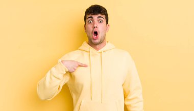 Şok olmuş ve ağzı açık, kendini işaret eden genç yakışıklı bir adam.
