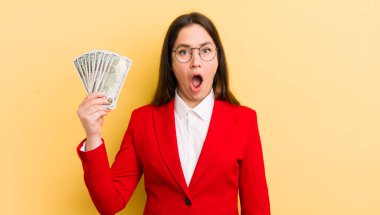 Genç ve güzel bir kadın çok şaşırmış ya da şaşkın görünüyor. para kavramı