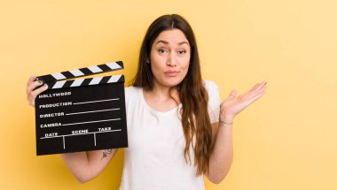 Genç ve güzel bir kadın şaşkın, şaşkın ve şüpheci hissediyor. Sinema alkışlama konsepti