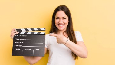 Genç, güzel bir kadın neşeyle gülümsüyor, mutlu hissediyor ve bir tarafı işaret ediyor. Sinema alkışlama konsepti