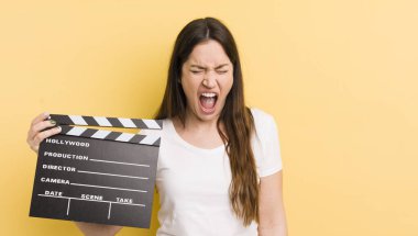 Genç ve güzel bir kadın agresif bir şekilde bağırıyor, çok kızgın görünüyor. Sinema alkışlama konsepti