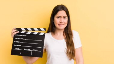 Genç, güzel bir kadın kafası karışmış ve şaşkın görünüyor. Sinema alkışlama konsepti