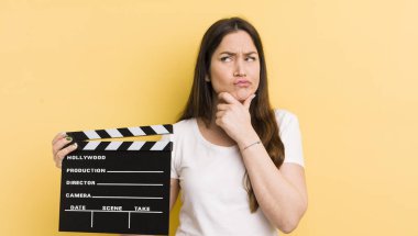 Genç, güzel bir kadın düşünüyor, kuşkulu ve şaşkın hissediyor. Sinema alkışlama konsepti