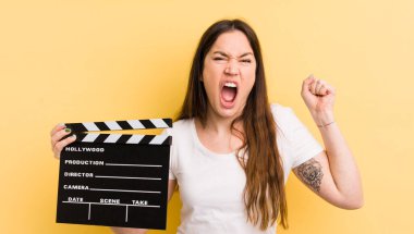 Genç ve güzel bir kadın sinirli bir ifadeyle agresif bir şekilde bağırıyor. Sinema alkışlama konsepti