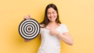 Genç, güzel bir kadın neşeyle gülümsüyor, mutlu hissediyor ve bir tarafı işaret ediyor.