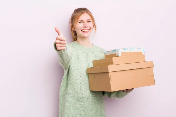 赤毛の可愛い女の子は誇りに思ってる親指を上げて積極的に笑ってる 配送ボックスのコンセプト — ストック写真