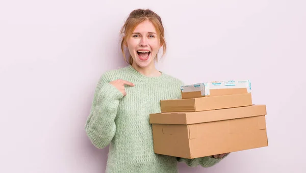 赤頭の可愛い女の子は幸せな気分で興奮して自己を指してる 配送ボックスのコンセプト — ストック写真