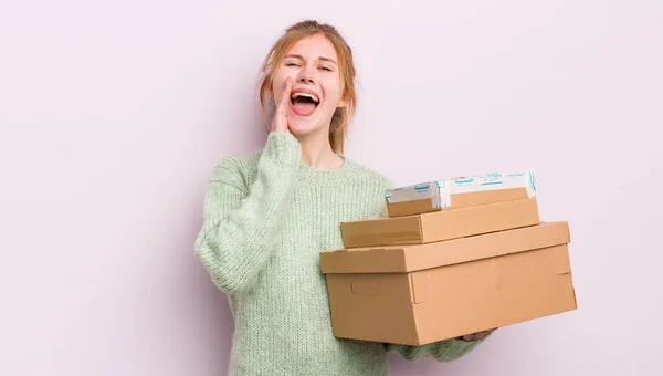 赤毛の可愛い女の子は幸せな気分だ口の横で大きな声を出す 配送ボックスのコンセプト — ストック写真