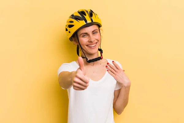 young pretty woman feeling proud,smiling positively with thumbs up. bike concept