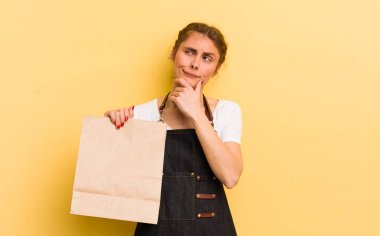 Genç, güzel bir kadın düşünüyor, kuşkulu ve şaşkın hissediyor. Fast food kurye konsepti