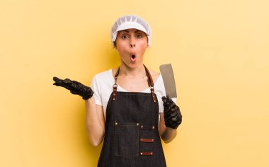 Genç ve güzel bir kadın şaşırmış ve şok olmuş görünüyor. Çenesi düşmüş ve elinde bir nesne tutuyor. Kasap konsepti