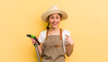 Genç ve güzel bir kadın kendini mutlu hissediyor ve heyecanlı bir şekilde kendini işaret ediyor. gardering konsepti