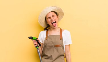 Neşeli ve asi tavırları olan genç ve güzel bir kadın, şaka yapıyor ve dilini dışarı çıkarıyor. gardering konsepti