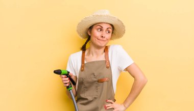 Genç, güzel bir kadın omuz silkiyor, kafası karışık ve kararsız. gardering konsepti