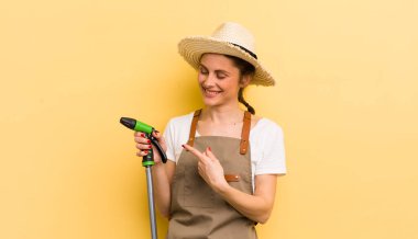 Genç, güzel bir kadın neşeyle gülümsüyor, mutlu hissediyor ve bir tarafı işaret ediyor. gardering konsepti