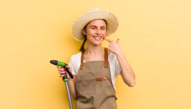 Genç ve güzel bir kadın, kendine güvenerek gülümsüyor. gardering konsepti