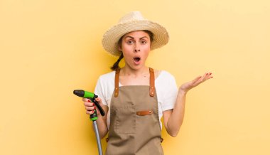 Genç ve güzel bir kadın şaşırmış ve şok olmuş görünüyor. Çenesi düşmüş ve elinde bir nesne tutuyor. gardering konsepti