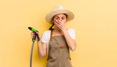 Genç ve güzel bir kadın şok olmuş bir şekilde elleriyle ağzını kapatıyor. gardering konsepti