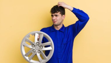 Kafası karışmış, kafası karışmış, kaşınan genç, yakışıklı bir adam. araba tamircisi konsepti