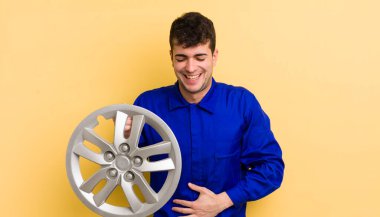 Genç yakışıklı bir adam komik bir şakaya yüksek sesle gülüyor. araba tamircisi konsepti